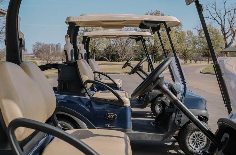 Golf cart fleet staged on a cart path at a golf course before the first tee time