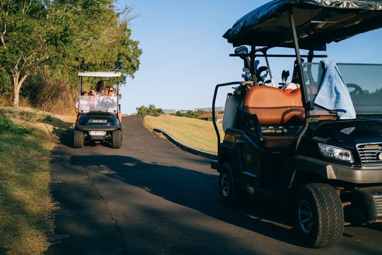 Two golf carts with bags on a course path at golden hour